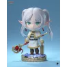 Frieren en version chibi, avec son bâton magique et sa mallette, sur un socle fleuri au rendu délicat.