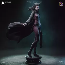 Re-L Mayer représentée debout sur son socle, vêtue de son corset violet, de son pantalon ajusté et de son long manteau flottant.