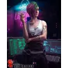 Judy Alvarez en tenue cyberpunk, cigarette à la main, devant une station informatique illuminée par des néons verts et magenta