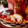 À l’arrière du socle, un petit chat sommeille paisiblement parmi les vêtements et les bagages